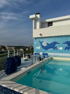 里乔内Augustus Hotel Riccione的一座拥有恐龙壁画的建筑屋顶上的游泳池