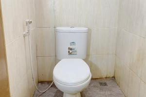 Un baño con un inodoro blanco en una cabina. en Central House Karimunjawa Mitra RedDoorz, en Karimunjawa
