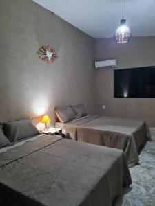 Una habitación con dos camas y un televisor en la pared. en Flat à beira-mar na praia de Antunes, en Maragogi