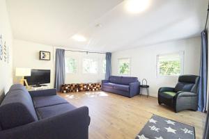 a living room with two blue couches and a television at Bigge Elements Gästehaus am Biggesee in Olpe