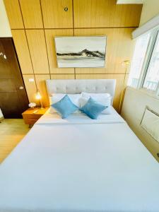 une chambre avec un grand lit blanc avec des oreillers bleus dans l'établissement 15 Elegant Urban Suite, à Cari Mayor