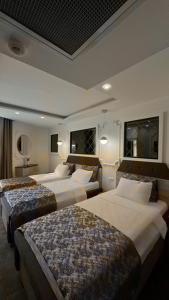 una camera d'albergo con tre letti in una stanza di AYDINLI HOTEL ad Amasya Altre 25 foto