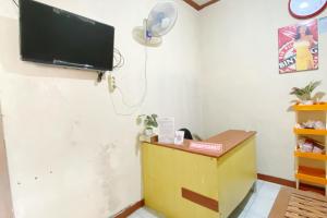Una habitación con un televisor de pantalla plana en una pared. en Central House Karimunjawa Mitra RedDoorz, en Karimunjawa