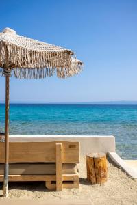 a straw umbrella and logs on the beach at MAKO Sea & Suites in Pefkochori