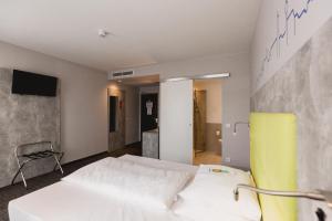 a bedroom with a white bed and a yellow chair at SleepySleepy Hotel Dillingen in Dillingen an der Donau