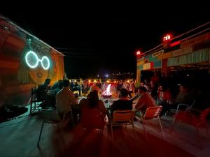 a group of people sitting at tables at night at taman'art space in Aït Benhaddou