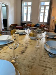 a wooden table with wine glasses and plates on it at Maison de charme 1920 in Roubaix