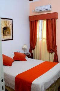 a bedroom with a bed with orange sheets and a window at Rutas Hotel in Salta