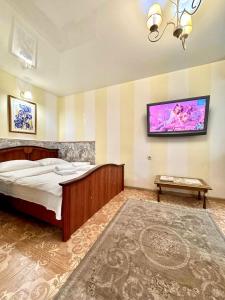 a bedroom with a bed and a tv on the wall at ApartPoltava Французький шик у центрі Полтави, 4 спальних місця, Корпусний парк in Poltava