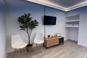a living room with two white chairs and a tv at El Alpendre in Moya
