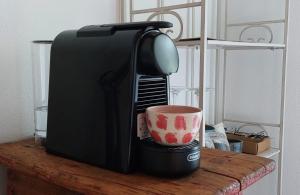 Eine Kaffeemaschine mit einer Tasse stand auf einem Tisch. in der Unterkunft La Grubla un rifugio nel bosco in Mergozzo