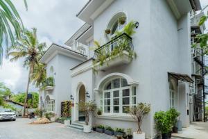 a white house with a balcony and palm trees at ELIVAAS 5 BHK Pet Friendly with Pvt Pool - Villa Vacasa in Calangute