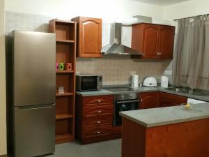 a kitchen with a stainless steel refrigerator and wooden cabinets at Luxury 4 bed villa Paphos in Mesogi