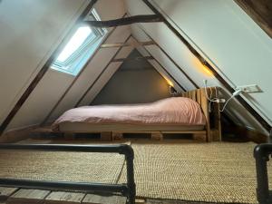 a bedroom with a bed in the attic at Tiny House De Smederij in Peize