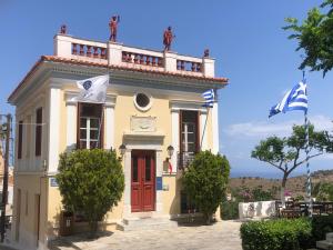 a yellow building with a red door and two flags at ARIA Kea Sunset Homes in Milopótamos