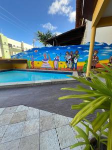 a mural on the side of a building with a swimming pool at Pousada Mangai in João Pessoa