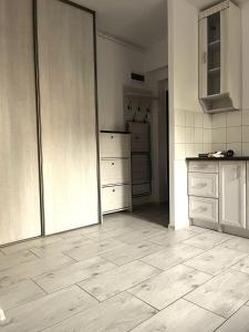 a kitchen with white cabinets and a tiled floor at Apartament 01 in Poznań