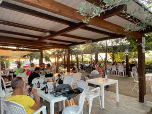 a group of people sitting at tables in a restaurant at Appartamenti Pousada Michelino in Parghelia