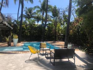 a group of chairs sitting next to a swimming pool at La villa de Claude, charmante villa créole Etang Salé les Bains in Étang-Salé les Bains