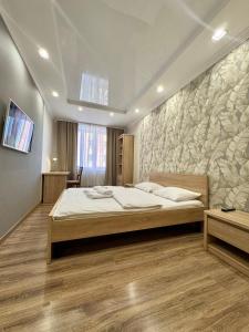 a bedroom with a bed and a stone wall at ApartPoltava Cучасні 2-кімн апартаменти з великою кутовою ванною ЦЕНТР МІСТА in Poltava