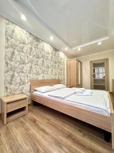 a bedroom with a large bed and a stone wall at ApartPoltava Cучасні 2-кімн апартаменти з великою кутовою ванною ЦЕНТР МІСТА in Poltava