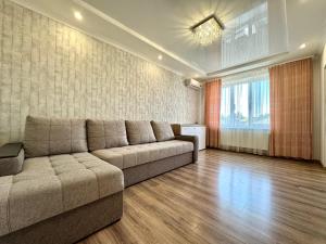 a living room with a couch and a large window at ApartPoltava Cучасні 2-кімн апартаменти з великою кутовою ванною ЦЕНТР МІСТА in Poltava