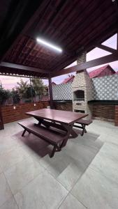a picnic table on a patio with a fireplace at Chalé Lazer Gravatá com 3 suítes - na Suíça Brasileira in Gravatá