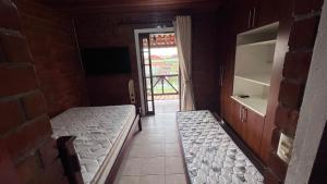 a room with two beds and a door to a room with a window at Chalé Lazer Gravatá com 3 suítes - na Suíça Brasileira in Gravatá +19 photos