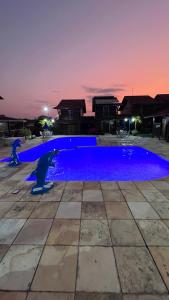 a large blue swimming pool at night at Chalé Lazer Gravatá com 3 suítes - na Suíça Brasileira in Gravatá