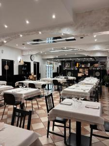 a restaurant with white tables and chairs in a room at Locanda San Martino in Collecchio