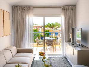 a living room with a couch and a television and a balcony at Resitour - Limnaria Gardens Apartments in Paphos