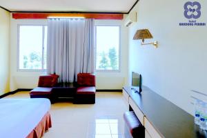 任抹Bandung Permai Hotel Jember的一间带一张床和两把椅子的酒店房间