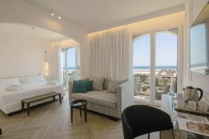 a bedroom with a bed and a couch and windows at Hotel De Londres in Rimini
