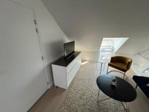 ein Wohnzimmer mit einem TV, einem Tisch und einem Stuhl in der Unterkunft Appartement neuf proche gare in Margny-lès-Compiègne