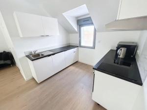 eine kleine Küche mit weißen Schränken und einer Spüle in der Unterkunft Appartement neuf proche gare in Margny-lès-Compiègne + 4 Fotos