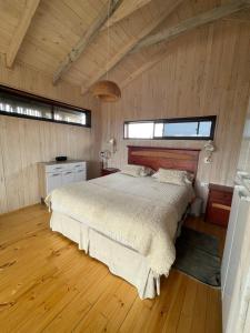 a bedroom with a bed in a room with wooden floors at Cabaña Pangal in Pichilemu