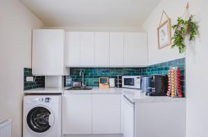 Una cocina con gabinetes blancos y lavadora. en Luxury 2 Bed in Reading - Free Parking & Fast Wi-Fi, en Reading