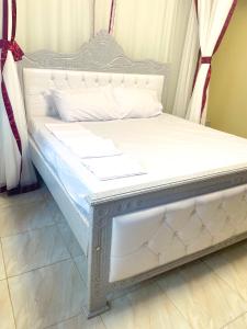 a bed with a white bed frame in a room at Cozy Residence III 2bedroom Apartment near Speke Resort in Kampala