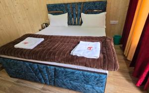 a bed in a room with two towels on it at Yamuna Pug Pinewood Greh by StayApart in Kharsālī +1 photo