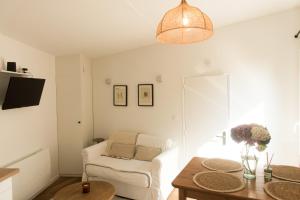a living room with a white chair and a table at Le Cabanon Malouin in Saint Malo