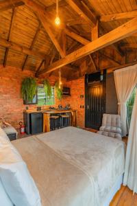 a bedroom with a large bed and a kitchen at Recanto Ágape in Santo Amaro da Imperatriz