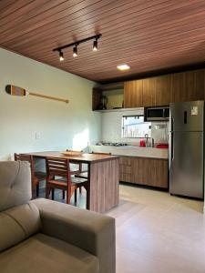 a kitchen with a table and a stainless steel refrigerator at Villa Maia Beach - Duplex in São Miguel dos Milagres