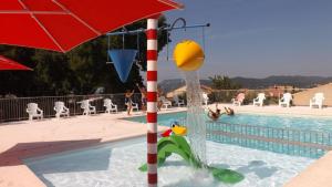 a pool with an umbrella and people playing in the water at Camping les Oliviers in Oraison
