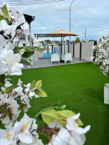 a garden with green grass and white flowers at LaRinDa Teluk Kemang Private Pool - Islamic in Port Dickson