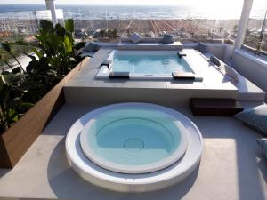 a bathroom with a tub and a swimming pool at Hotel De Londres in Rimini
