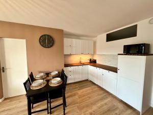 ルマンにあるChez Béranger - proche Gare et Palais des Congrèsのテーブルと壁に時計があるキッチン +3枚の写真
