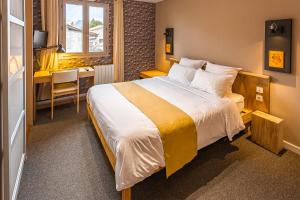 a hotel room with a large bed and a desk at Résidence L'Atelier in Ennezat