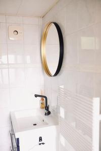 ein weißes Badezimmer mit Waschbecken und Spiegel in der Unterkunft Heerlijk huisje op de Veluwe in Putten in Putten