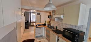 une petite cuisine avec un évier et un micro-ondes dans l'établissement Le Duo Thermal, à Plombières-les-Bains