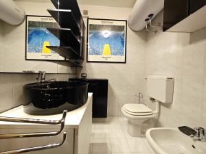 une salle de bain avec une baignoire noire et des toilettes dans l'établissement Hostdomus - Pastore Apartment, à Sestrières